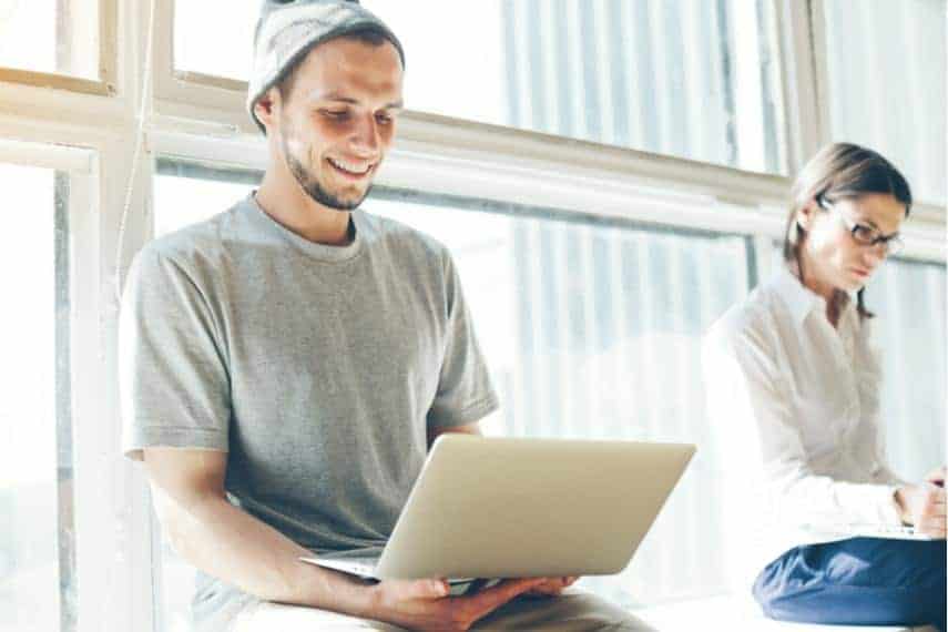 man and woman sitting and working on laptops