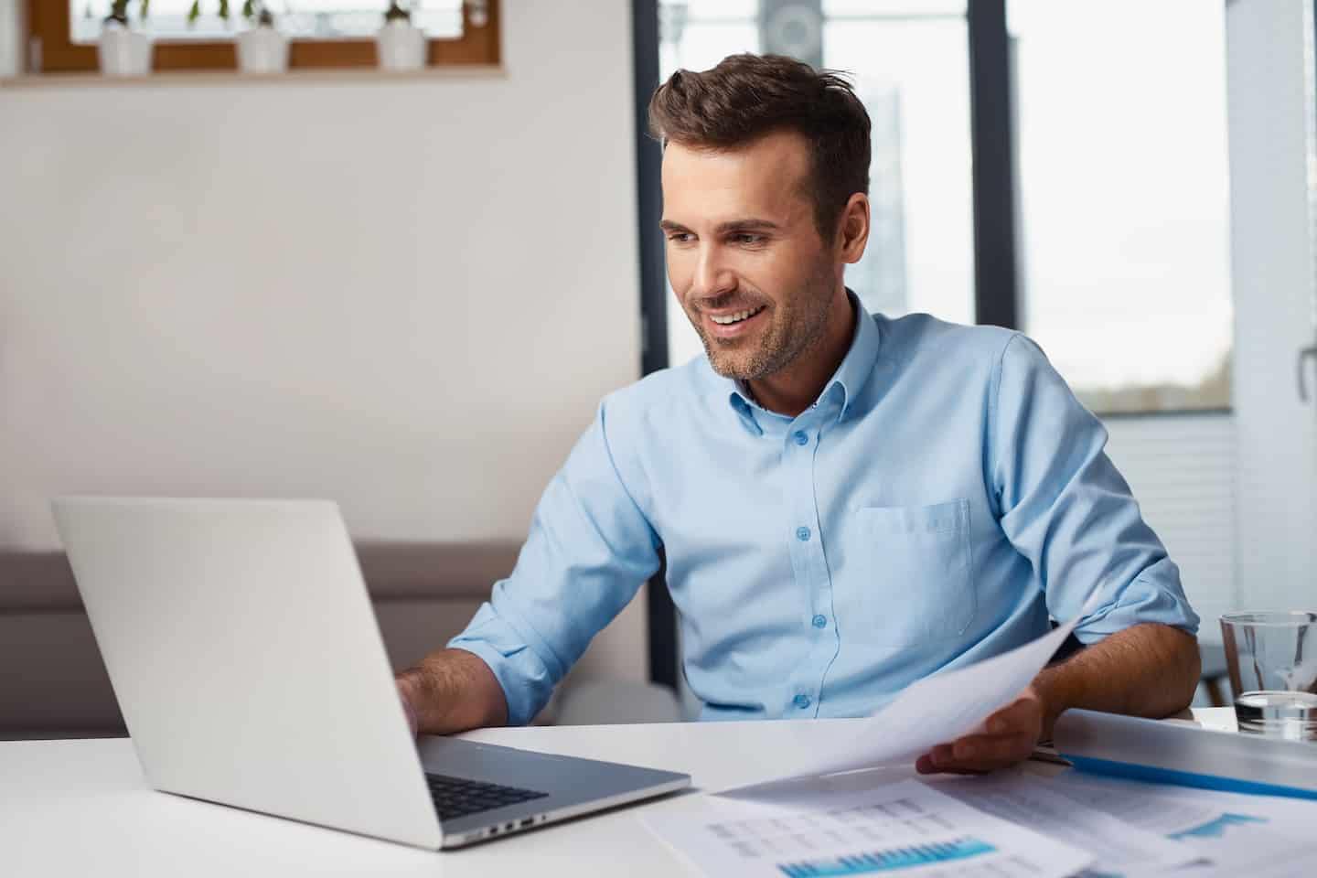 man holding bank statement in front of laptop
