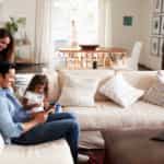 young family sitting on the couch while dad is holding a tablet