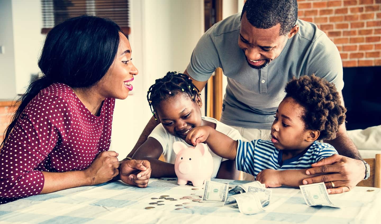 family sitting at table counting money in a piggy bank