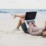 how to plan a small scale business person laying on the beach working on laptop