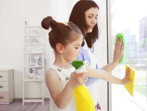 mom and daughter washing windows together