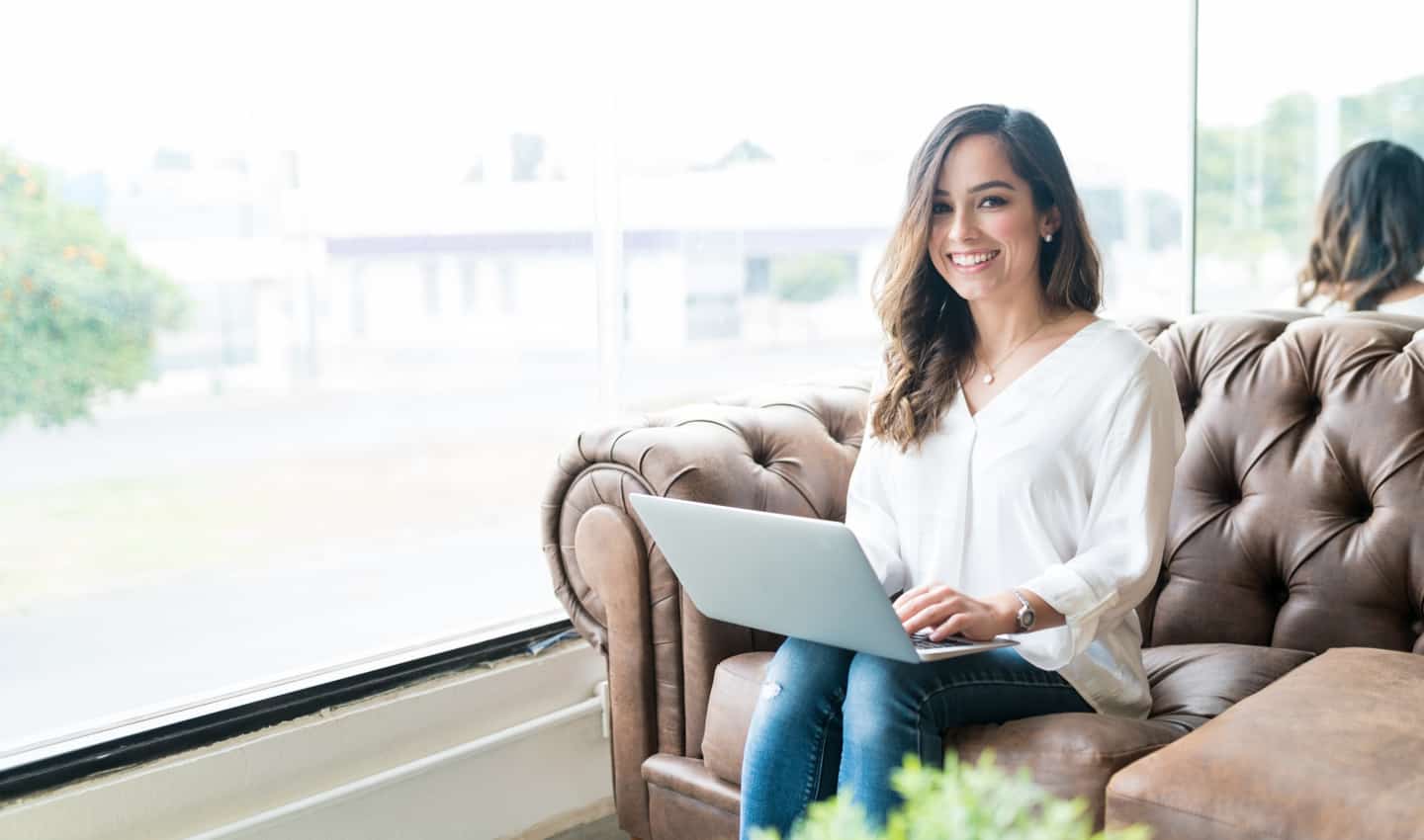 woman sitting on loveseat with laptop