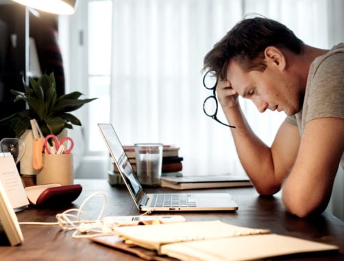 Man working on his laptop and showing visible signs of stress