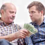 elderly man lending money to his adult son