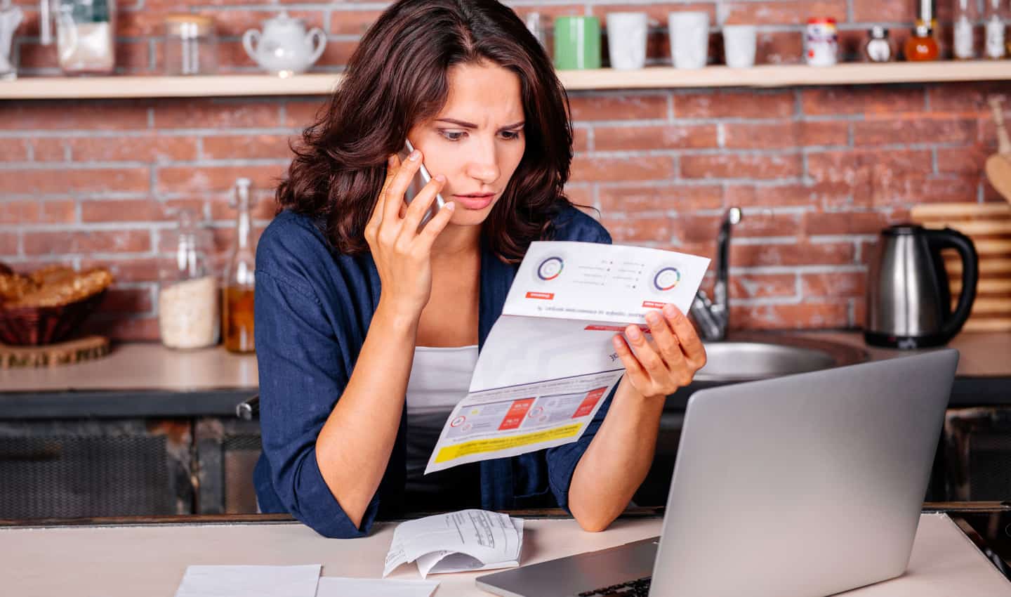 woman on the phone looking at paper bill