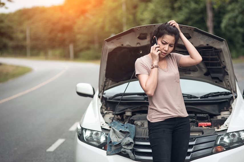 young woman with broken car calling for help