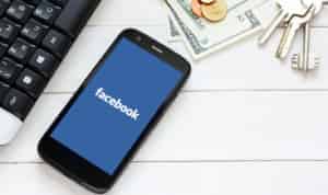 Facebook on mobile screen next to cash