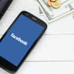 Facebook on mobile screen next to cash