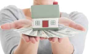 woman holding a house and cash in her palms