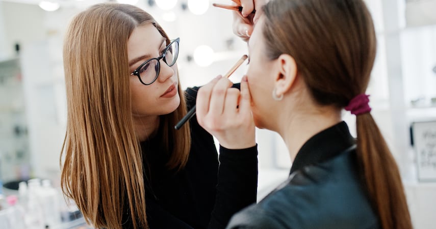 woman doing another woman's makeup AS photo studio