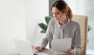 woman sorting through finances on paper and laptop