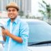 man standing by car holding smartphone