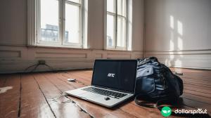 A laptop sitting on a bare wooden living room floor, representing the risk that entrepreneurs take when venturing out on their own.