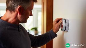 A dad adjusting the thermostat in the hallway.