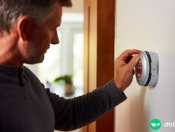 A dad adjusting the thermostat in the hallway.