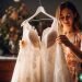 A woman looking at her wedding dress on a hanger.