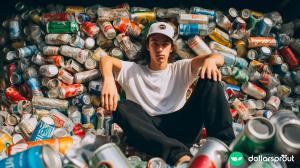 A teenager sitting in a huge pile of aluminum cans, almost as if he is showing off.