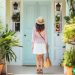 A house sitter walking up to the front door of a cute little white and blue house.