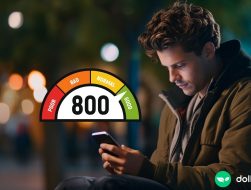 A man wearing a coat and looking down at his phone. There is a credit score graphic overlaid on top of the image, showing that 800 is a very high credit score.