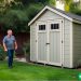 A suburban dad looking at a shed in his well maintained backyard.