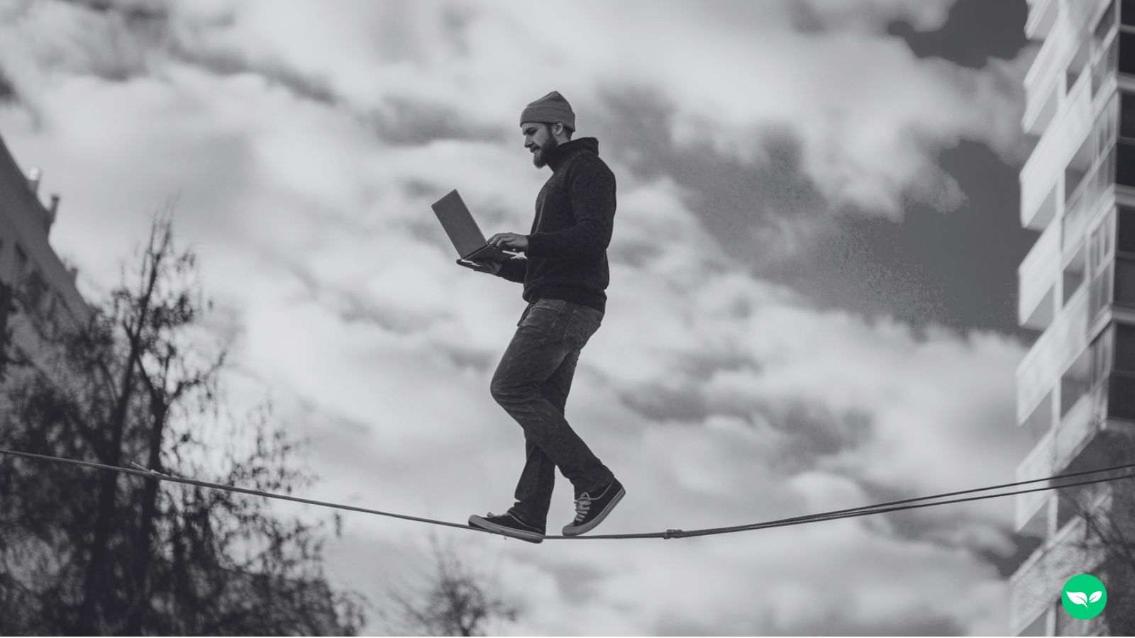 A man walking on a tightrope and looking at his laptop.