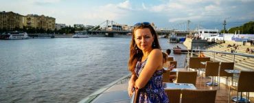 Yulia standing at a railing overlooking a river.