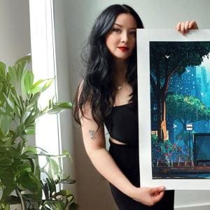 A photo of Laura El posing with one of her prints.