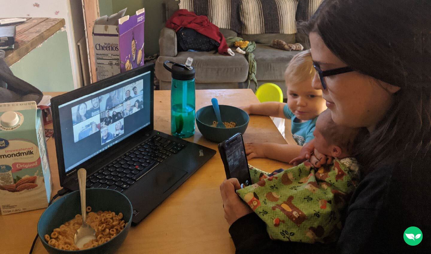 nicole magelssen holding her two boys at home at the kitcken table while on a zoom call with her virtual assistant agency