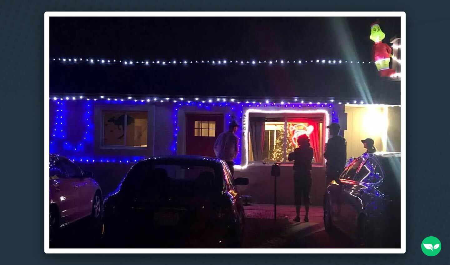 One-storey house decorated with blue and white Christmas lights, people with several silhouettes gathered in front.