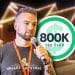 Steve Hunsaker, founder of a seasonal light-hanging side hustle, speaks into a microphone while wearing a Valley Christmas Lights t-shirt. A house lit with holiday lights glows in the background.