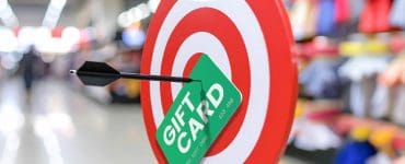 Bullseye target with a green gift card and black arrow, symbolizing hitting your goal with free Target gift cards.