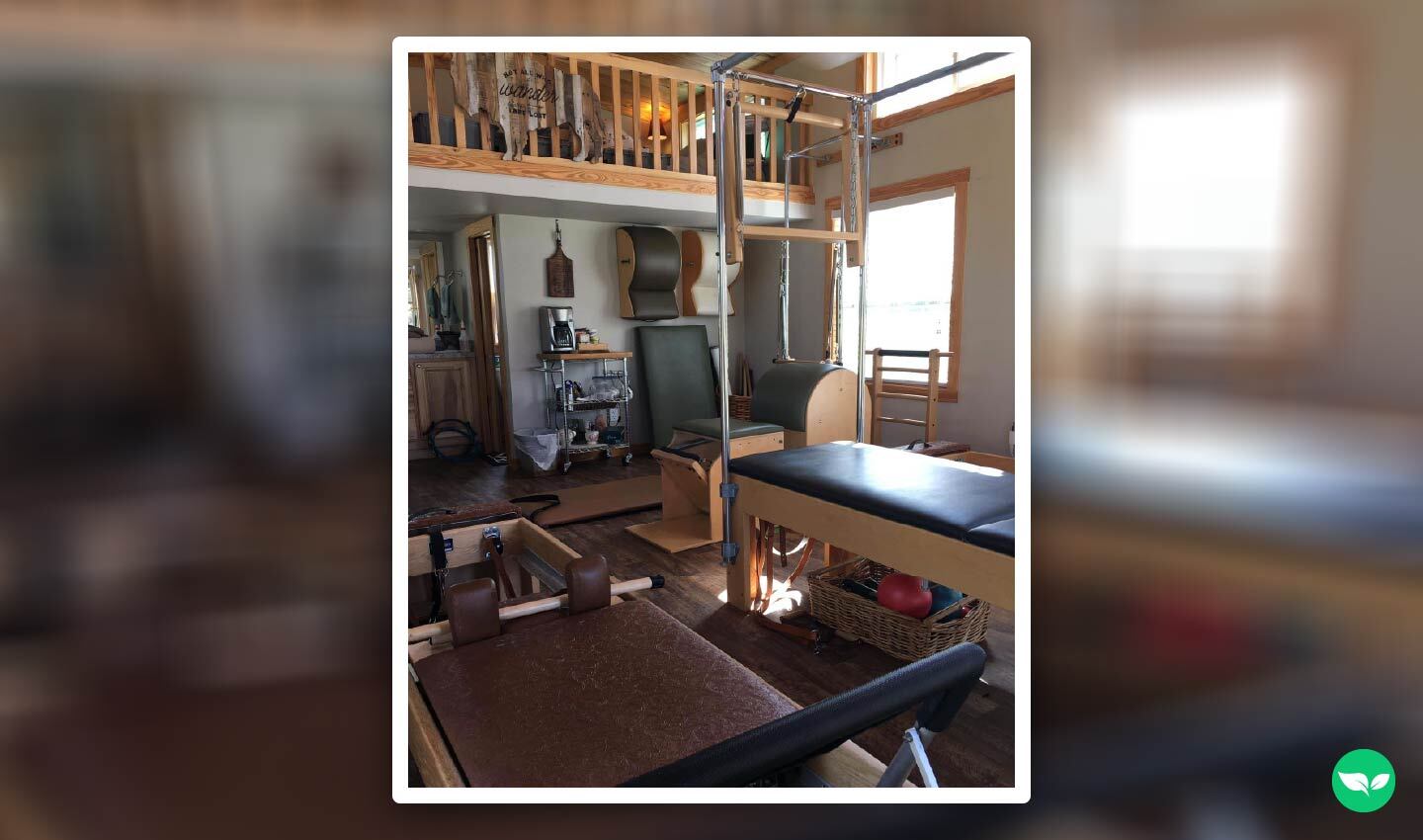 Interior of Melody Morton-Buckleair’s tiny home Pilates studio, showing reformers, barrels, and other professional equipment beneath a loft.