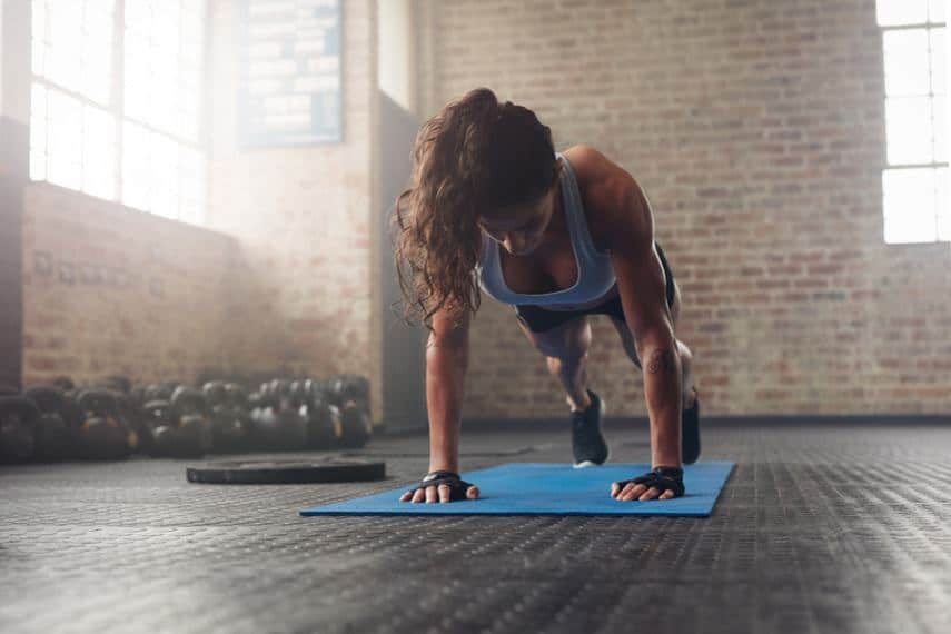 athletic woman doing push ups on workout mat